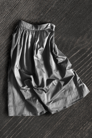 Crumpled gray skirt lying on dark wooden backgroundの写真素材