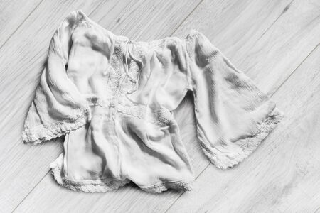 White ethnic linen blouse lying on white wooden backgroundの写真素材