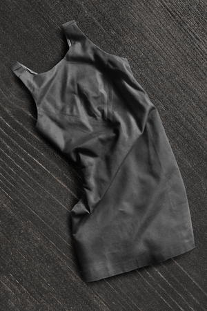 Black basic dress lying on dark wooden backgroundの写真素材
