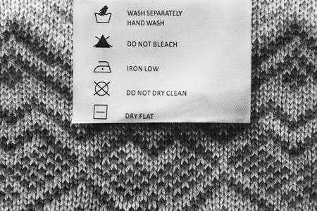 Washing instructions clothes label on gray knitted backgroundの写真素材