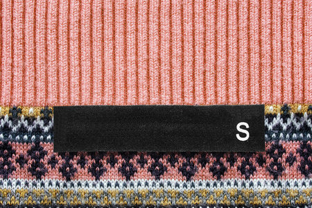 Black clothes label on colorful knitted background closeup
