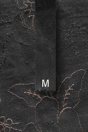 Black clothes label on black embroidered linen as a backgroundの写真素材