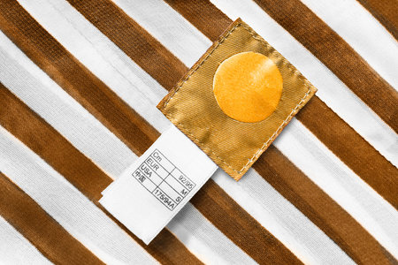 Clothes label on white and brown striped silk as a backgroundの写真素材