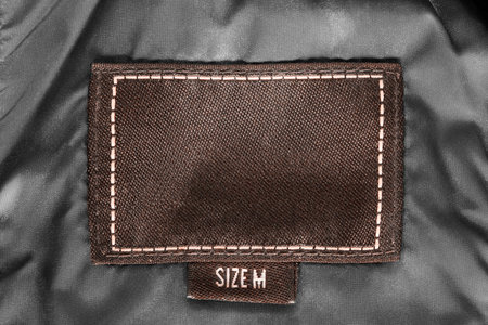Clothes label lettered size M on black satin closeup