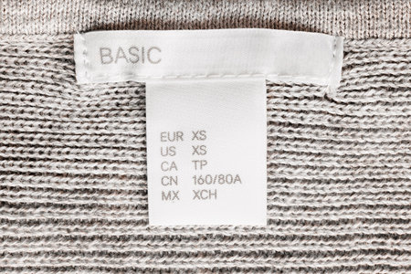 XS size clothes label lettered basic on knitted background