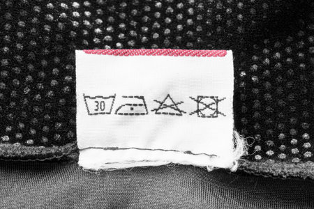 Washing instructions clothes label on black textile background closeup