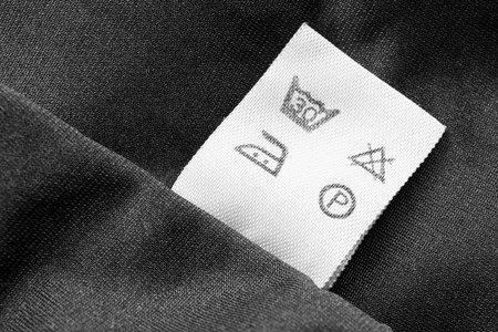 Washing instructions clothes label on black textile backgroundの写真素材