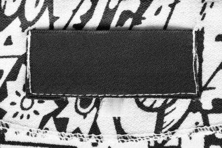 Blank black clothes label on black and white textile backgroundの写真素材