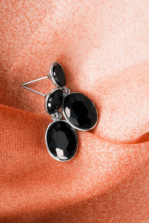 Black obsidian elegant earrings on orange folded clothの写真素材