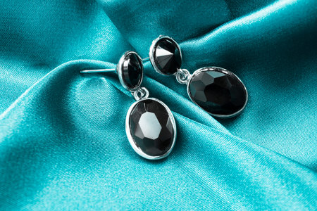 Elegant black onyx earrings on crumpled blue satin closeupの写真素材