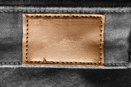 Blank brown leather clothes label on black denim as a backgroundの写真素材