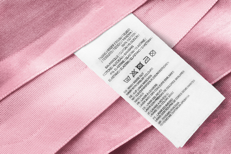 Washing instructions and fabric composition clothes label on pink satin as a backgroundの写真素材