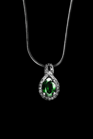 Emerald pendant with diamonds hanging on silver chain isolated over blackの写真素材