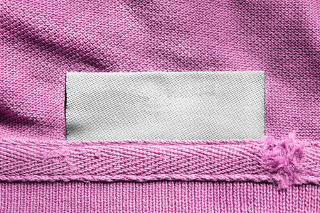Blank textile clothes label on pink textile background