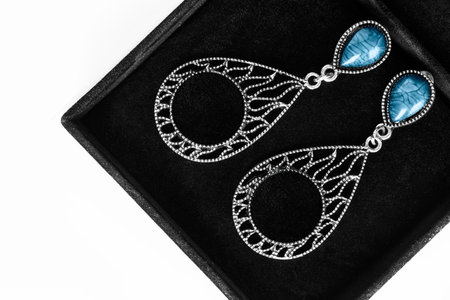 Carved silver earrings with turquoise gems in black jewel box closeupの写真素材
