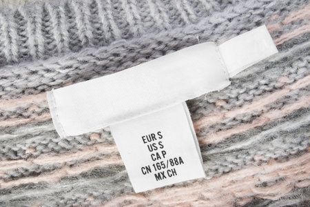 Small size textile clothes label on wool knitted background closeup