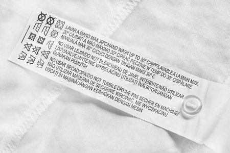 Washing instructions clothes label on white cotton background closeup