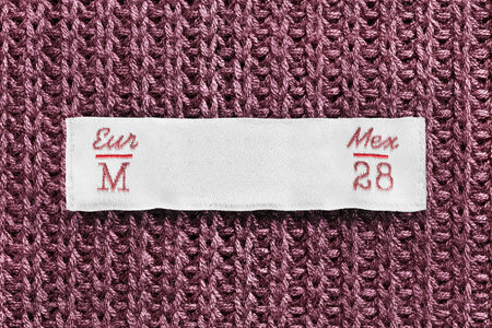 Medium size textile clothes label on pink knitted background