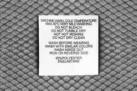Fabric composition and washing instructions clothes label on synthetic textile background