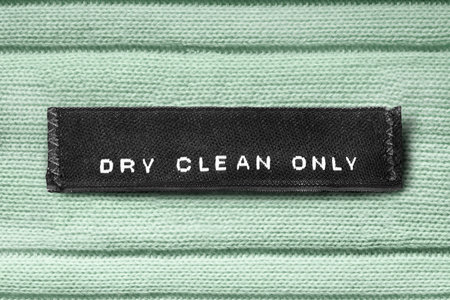 Clothes label lettered dry clean only on green knitted background