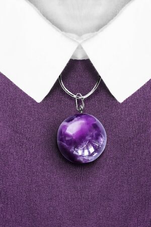 Elegant amethyst ball pendant on silver chain on purple knitted pullover with white collarの写真素材