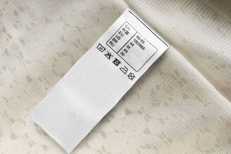 Washing instructions size M clothes label on beige textile background closeupの写真素材