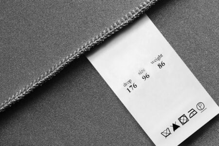 Washing instructions and size clothes label on black textile background closeupの写真素材