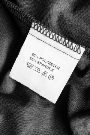 Content and care clothes label on black textile background closeup