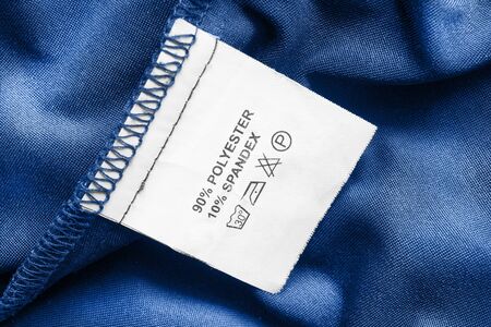 Content and care clothes label on blue textile background closeupの写真素材