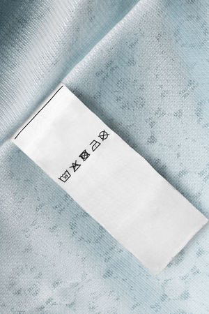 Care clothes label on pastel blue textile background closeupの写真素材
