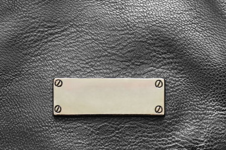 Blank metal label on black leather background closeupの写真素材