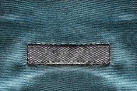 Blank textile clothes label on blue satin background