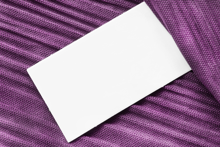 White blank clothes label on purple satin background closeupの写真素材