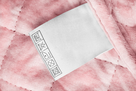 Care clothes label on pink textile quilted background closeupの写真素材