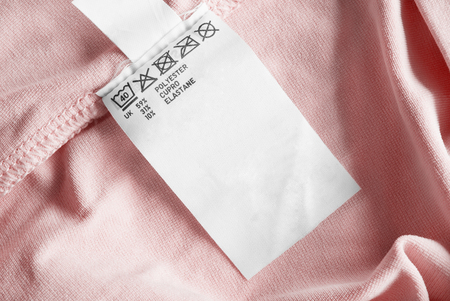 Care and composition clothes label on pastel pink textile backgroundの写真素材
