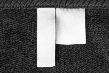 Blank white clothes labels on black textile background closeupの写真素材