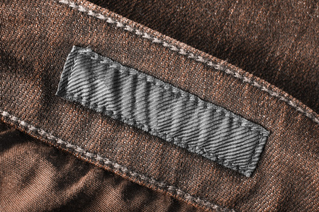 Blank textile clothes label on brown denim background closeupの写真素材