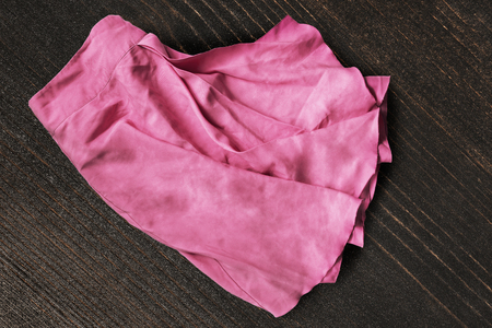 Crumpled pink silk skirt on dark brown wooden backgroundの写真素材
