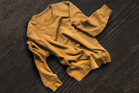 Crumpled yellow sweatshirt on dark brown wooden backgroundの写真素材