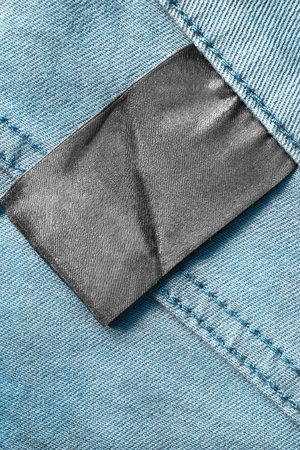 Blank black textile clothes label on blue denim background closeupの写真素材