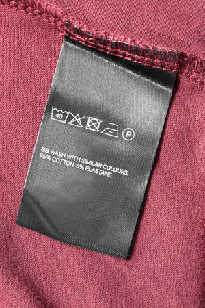 Care and composition clothes label on maroon textile background