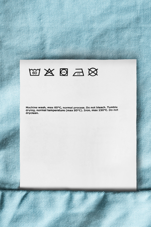 Care clothes label closeup on blue cotton backgroundの写真素材