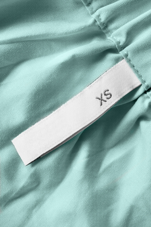 XS size clothes label on blue cotton background closeupの写真素材