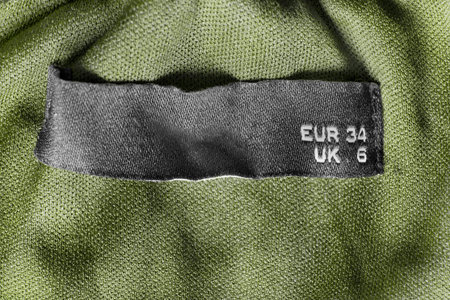 34 size clothes label on khaki green textile background closeup