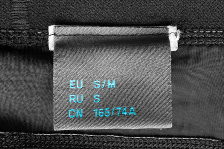 Small size clothes label on black textile synthetics background closeup
