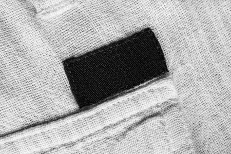 Blank black textile patch on white textile background closeup