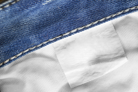 White blank clothes label on blue denim background closeupの写真素材