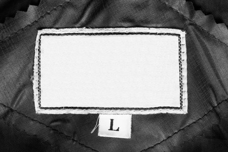 White blank textile L size clothes label on black background closeup