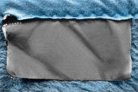 Blank textile clothes label on blue textile background closeup