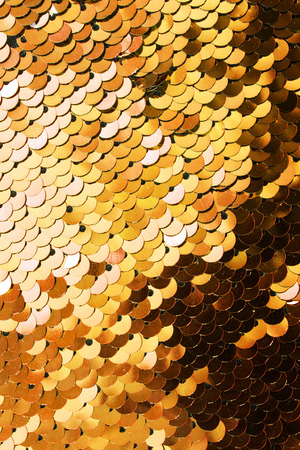 Golden shiny metallic sequins closeup as a backgroundの写真素材
